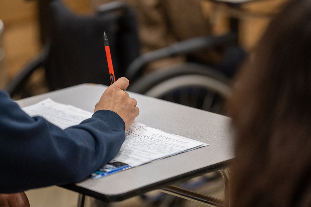 closeup of hand holding pencil at desk