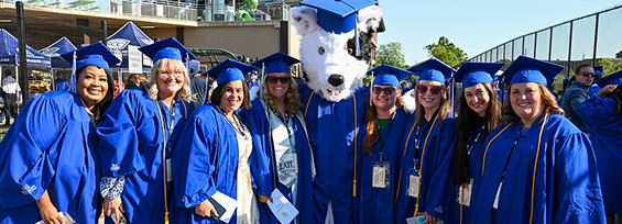Graduates in blue caps and gowns pose with the college mascot at Spartanburg Community College’s 2026 graduation ceremony.