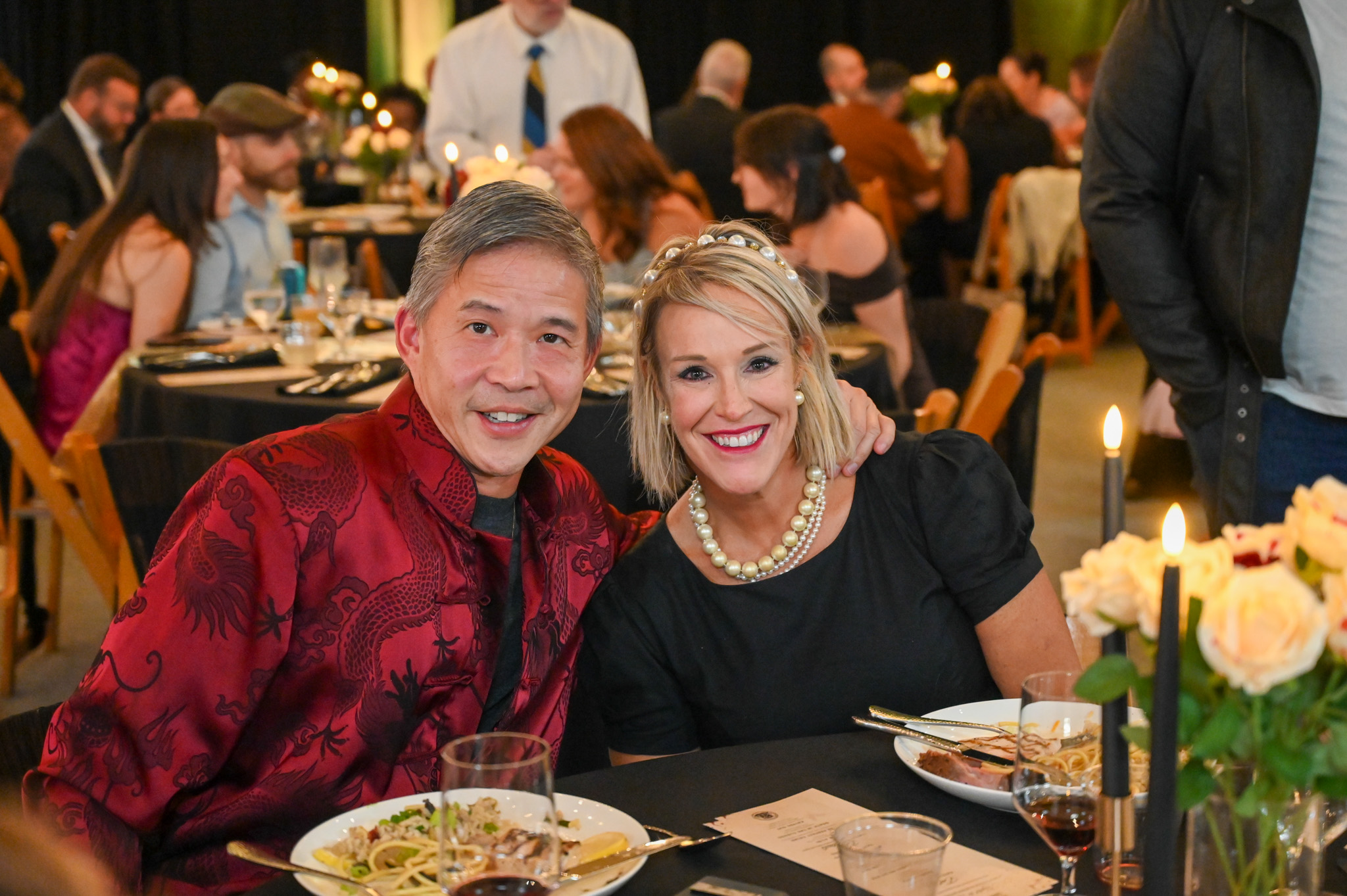 A couple sits at a elegant dinner table smiling together