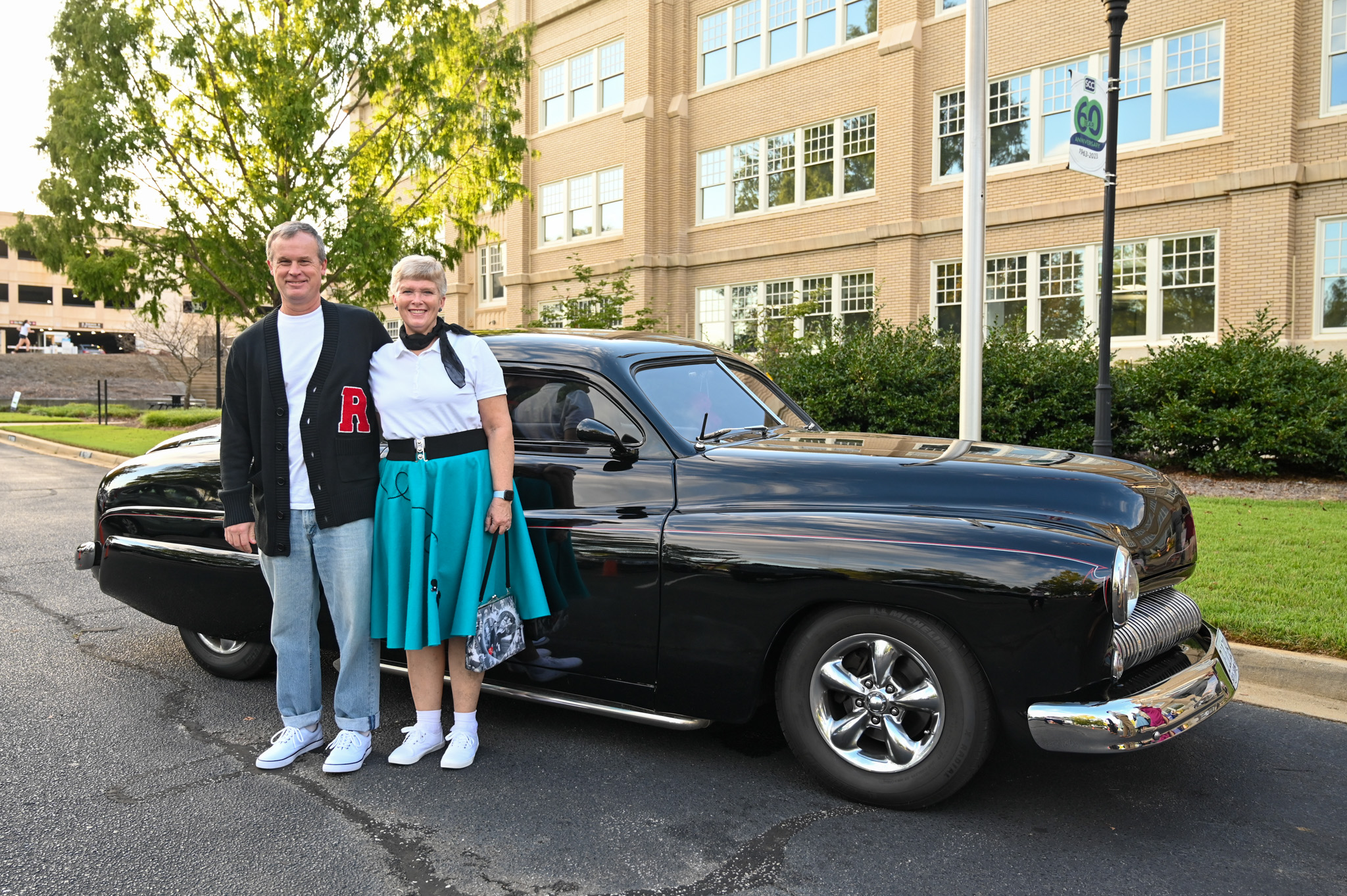 Guests enjoy the Murder Mystery Dinner at Spartanburg Community College, posing beside a vintage black car in elegant retro fashion. The pair’s stylish outfits and cheerful expressions capture the lively, nostalgic atmosphere of the college’s 1940s-themed evening event.