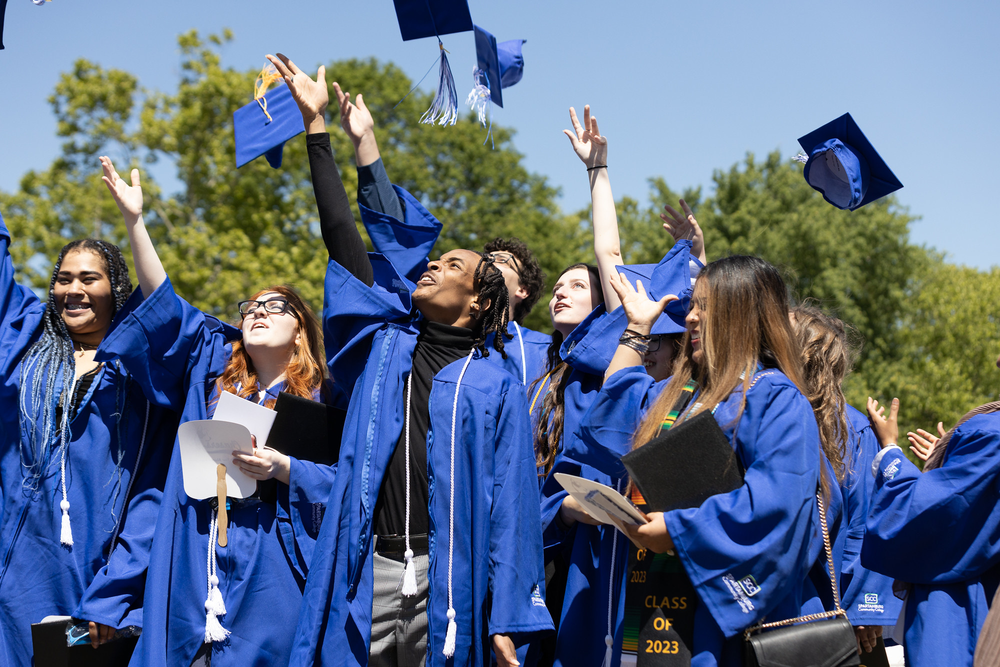 dual enrollment students at graduation tossing caps