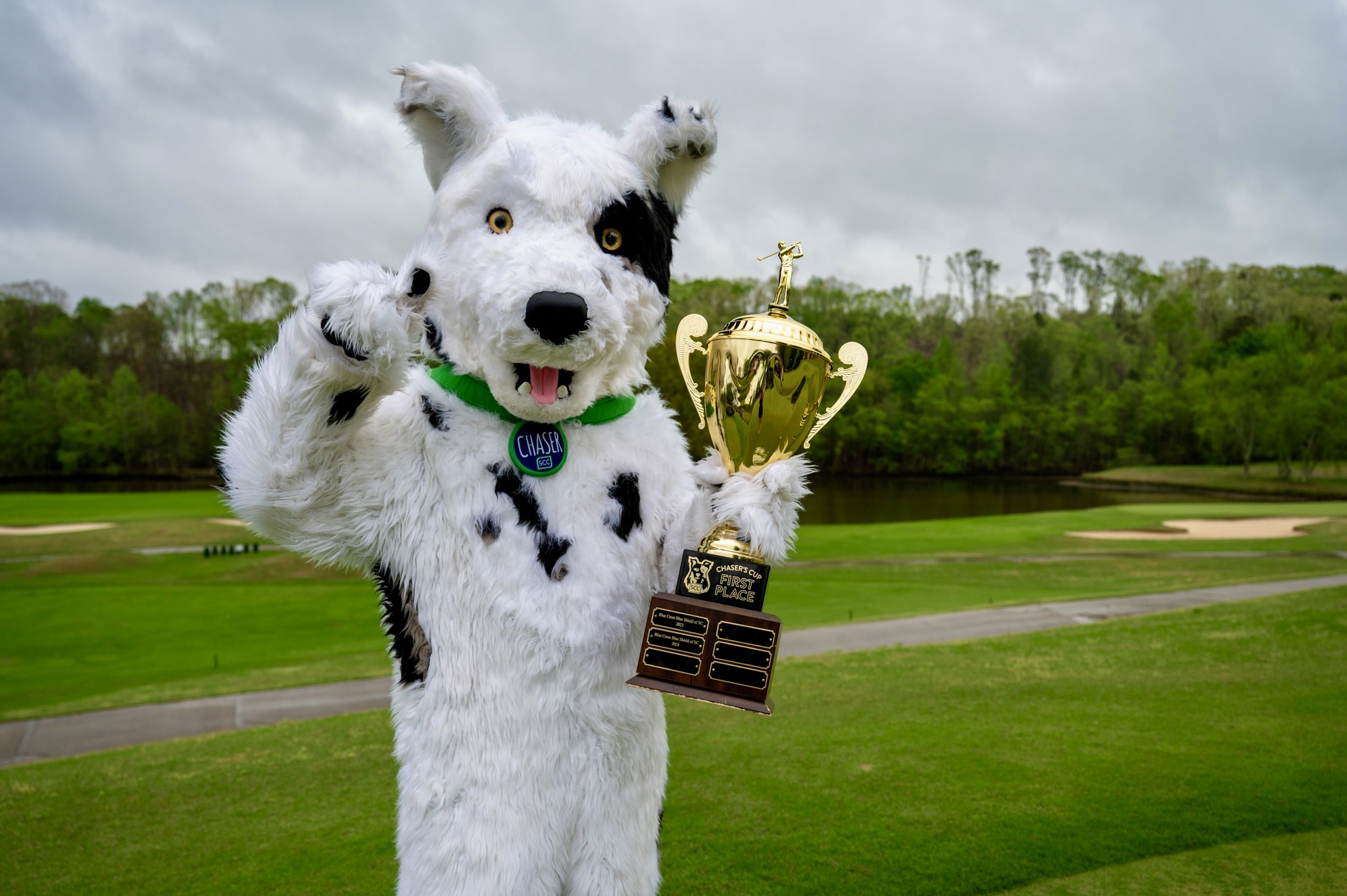 Chaser the mascot poses with the trophy for the Chaser's Cup Golf Tournament