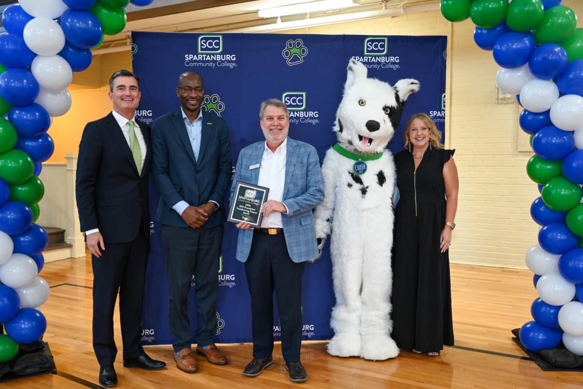 A group photograph at a Spartanburg Community College event featuring four representatives smiling alongside the 